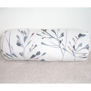 May include: White cylindrical pillow with a floral pattern in shades of gray, pink, and purple. The pattern features delicate branches with small leaves and buds.
