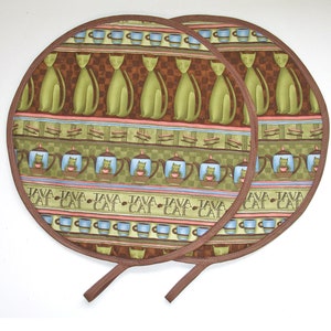 May include: Two brown and green fabric pot holders with a cat and coffee pot design. The pot holders have a brown trim and a brown strap.