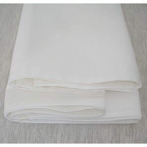 Peut inclure: Une nappe en lin blanche pliée en trois, montrant la texture lisse du tissu.