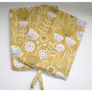 May include: Two yellow fabric pot holders with a white and grey floral pattern. The pot holders have a loop handle.