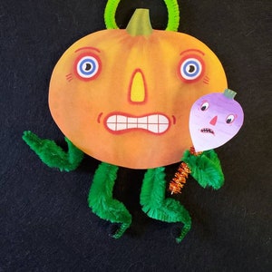 May include: A whimsical Halloween decoration featuring a cartoon pumpkin with a surprised expression, blue eyes, and a green pipe cleaner handle. It has green pipe cleaner arms and legs, and a purple turnip friend.