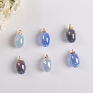 May include: Six iridescent oval-shaped glass charms with gold-tone tops. The charms are in shades of blue and purple.