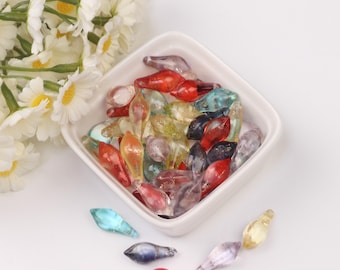 May include: A bowl filled with colorful glass beads in various shapes and sizes. The beads are translucent and have a shimmery finish.