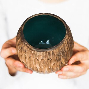May include: A brown ceramic bowl with a textured exterior and a teal green interior.