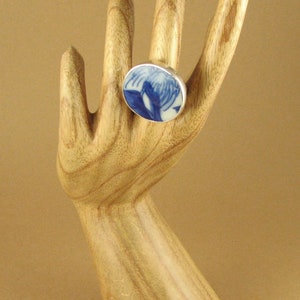 May include: A silver ring with a blue and white ceramic inlay. The inlay features a floral design.