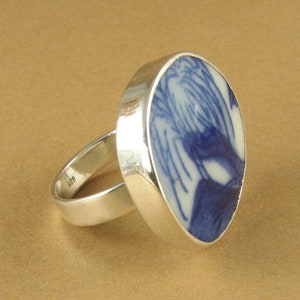 May include: A silver ring with a blue and white ceramic inlay. The inlay features a swirling pattern.