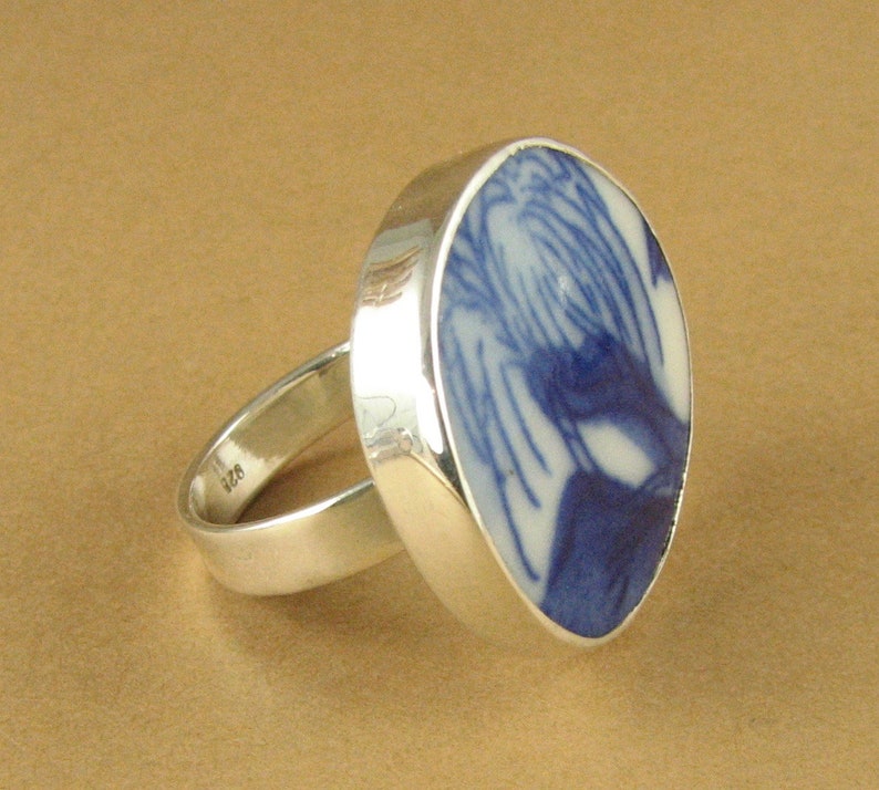 May include: A silver ring with a blue and white ceramic inlay. The inlay features a swirling pattern.