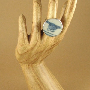 May include: A silver ring with a blue and white ceramic inlay featuring a bird design.