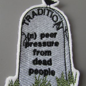 May include: Embroidered patch with a tombstone design. The tombstone is gray with black text that reads "Tradition", "In peer pressure from dead people". A black bird sits on top of the tombstone. Green grass is embroidered at the base of the tombstone.