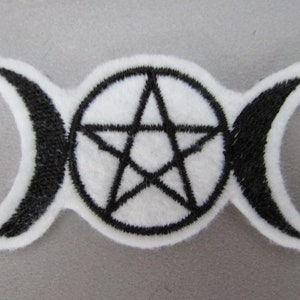 May include: A white felt patch with a black embroidered triple moon symbol and a pentagram in the centre.