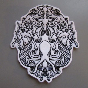 May include: Black and white embroidered patch featuring two mermaids flanking an octopus with seahorse details. The patch is on a white background.