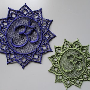 May include: Two embroidered lace patches with an Om symbol in the center. The larger patch is blue and the smaller patch is green.