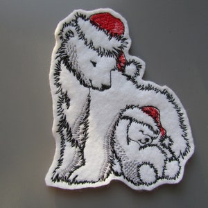 May include: Embroidered patch featuring two white polar bears wearing red Santa hats. The larger bear is standing and the smaller bear is sitting. Both bears are outlined in black thread.