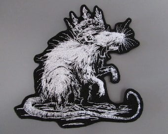 May include: A black and white embroidered patch featuring a detailed illustration of a rat wearing a crown. The rat is depicted in profile with textured fur, long whiskers, and a curled tail, set against a solid black background shape.