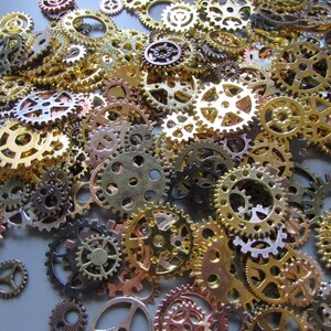 May include: A collection of various sized metal gears in shades of gold, bronze, and silver. The gears are scattered across a surface, creating a textured and detailed pattern. The gears have intricate designs and are suitable for steampunk or industrial-themed projects.