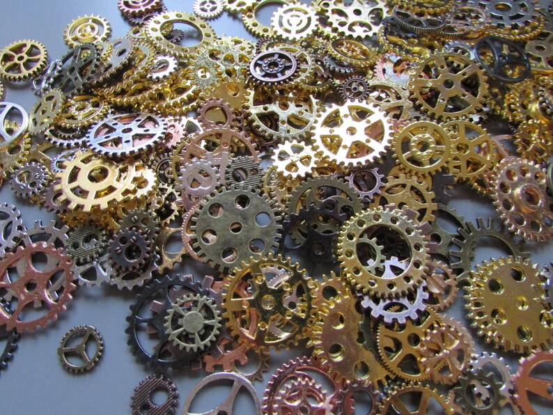 May include: A collection of various sized metal gears in shades of gold, bronze, and silver. The gears are scattered across a surface, creating a textured and detailed pattern. The gears have intricate designs and are suitable for steampunk or industrial-themed projects.