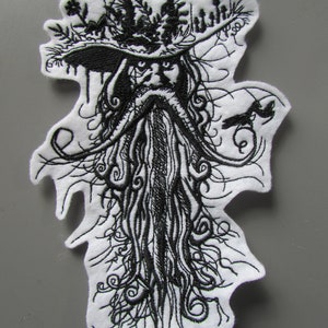 Könnte beinhalten: Schwarz-weiß gestickter Aufnäher mit einem bärtigen Mann, der einen Hut mit einem Blattdesign trägt. Der Bart des Mannes ist lang und fließend, und der Hut ist mit Blättern und Blumen verziert.