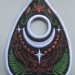 May include: Black felt ouija board with a white crescent moon, stars, and floral designs embroidered in red and green.