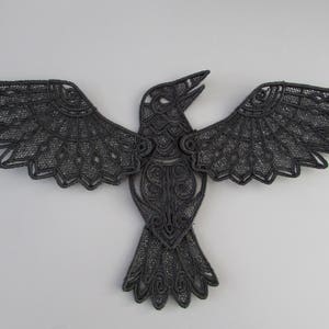May include: Black lace raven applique with intricate details. The raven is depicted with outstretched wings and a detailed body.