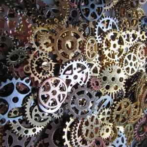May include: A collection of various sized metal gears in shades of gold, bronze, silver, and copper. The gears are arranged closely together, creating a textured, industrial aesthetic. The image showcases the intricate details and mechanical design of the gears.