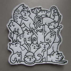 May include: A white felt patch with a black outline of a group of cats in various poses. The cats are all facing different directions and some are stacked on top of each other.