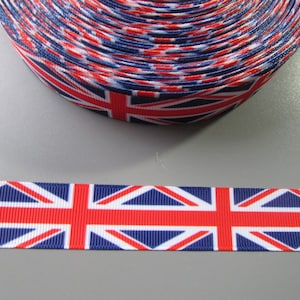 May include: Red, white and blue ribbon with a Union Jack pattern. The ribbon is rolled up and a single piece is laid out flat.
