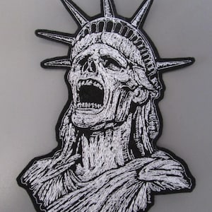 May include: Embroidered patch with a distressed design of the Statue of Liberty screaming, in black and white. The patch shows the statue's head and upper body, with detailed stitching for a textured look. Suitable for jackets, bags, or other fabric items.