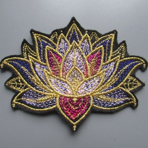 May include: An embroidered lotus flower patch in gold, purple and pink. The patch is on a black fabric background.