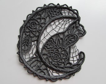 May include: Black lace applique featuring a crescent moon and a cat design. The design is intricate and detailed, with floral motifs throughout.