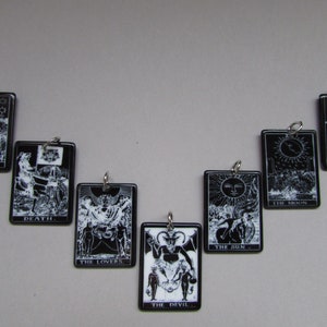 May include: Black and white tarot card charms with silver rings. The cards include The Star, Death, The Lovers, The Devil, The Sun, The Moon, and The Fool.