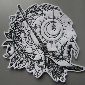 May include: Black and white embroidered patch featuring a witch's broom, a crescent moon, a spider web, and floral elements.