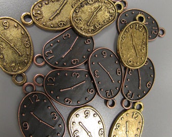 May include: A collection of 12 gold and black metal charms shaped like melting clocks. Each charm has a different time on the face, with some showing 12, 3, 6, or 9. The charms have a loop at the top for attaching to a necklace or bracelet.