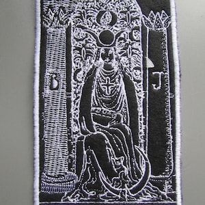 Puede incluir: Parche bordado en blanco y negro de la carta del tarot La Sacerdotisa. La carta presenta a una mujer sentada en un trono con una luna creciente sobre su cabeza. El texto "THE HIGH PRIESTESS" está en la parte inferior de la carta.