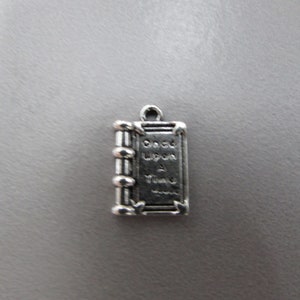 May include: Silver charm in the shape of a book with the words "Once Upon A Time" on the cover.