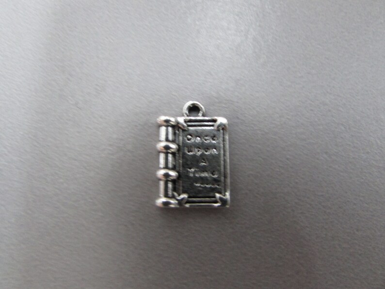 May include: Silver charm in the shape of a book with the words "Once Upon A Time" on the cover.