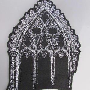 May include: Black patch with a white embroidered gothic arch design. The patch features intricate detailing, including pointed arches and decorative elements. The design is reminiscent of cathedral architecture.