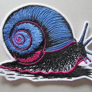 May include: Embroidered snail patch featuring a blue shell, black body, and pink detailing. The patch has a white border. Ideal for customising clothing, bags, or other fabric items.