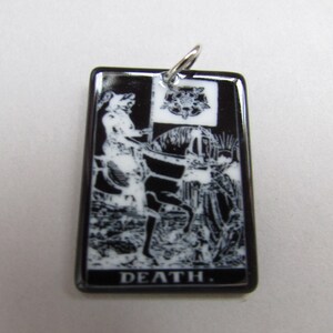 May include: Black and white ceramic pendant featuring a tarot card image of Death, a skeletal figure riding a white horse. The pendant has a silver bail and the word "DEATH" is printed in white at the bottom.