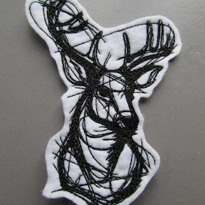 May include: Black and white embroidered patch of a deer head with antlers. The deer is stylised with a scribbled line design.