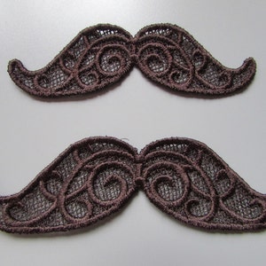 May include: Two brown lace mustache shapes. The lace is a delicate, intricate design with a swirl pattern.