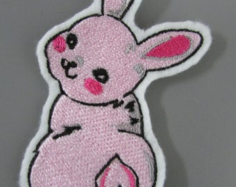 May include: Pink embroidered bunny rabbit patch with black and pink details. The bunny is sitting with its tail in the air.