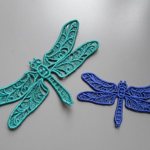 Puede incluir: Dos apliques bordados de libélula, uno turquesa y otro azul, con intrincados diseños de encaje.