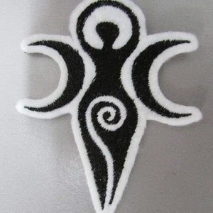 May include: Black and white embroidered patch featuring a stylised female figure with a spiral design and three crescent moons.