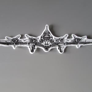 May include: Black and white embroidered patch of a vintage aeroplane with three propellers.