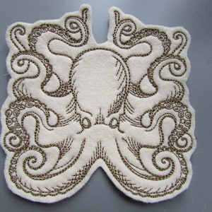 May include: A white felt patch with an embroidered brown octopus design. The octopus has eight tentacles with intricate details.