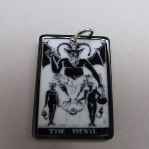 May include: Black and white tarot card pendant with a black border. The card depicts a devil with horns and a goat-like face. The card reads "THE DEVIL".