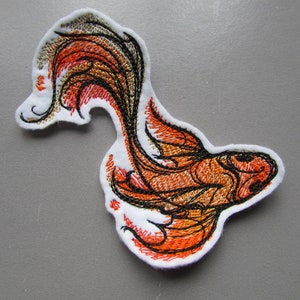 Peut inclure: Patch thermocollant brodé représentant un poisson rouge stylisé orange et noir avec une queue flottante.