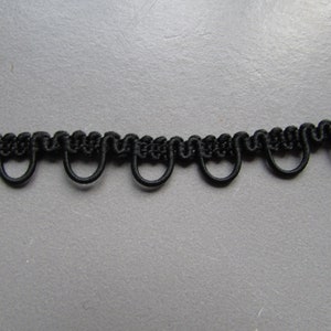 May include: Black trim with a series of small loops. This trim is made of a soft, flexible material and is perfect for adding a decorative touch to any project.