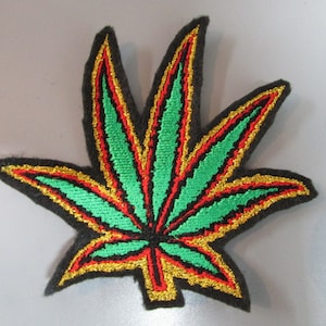 May include: Green, red and gold embroidered marijuana leaf patch. The patch is made of felt and has a black outline.