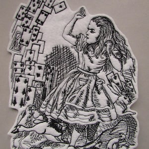 May include: A white fabric patch featuring a black embroidered illustration of a girl with long hair, surrounded by a flurry of playing cards, a rabbit, a bird, and other small creatures. The design is detailed with fine lines and intricate stitching.